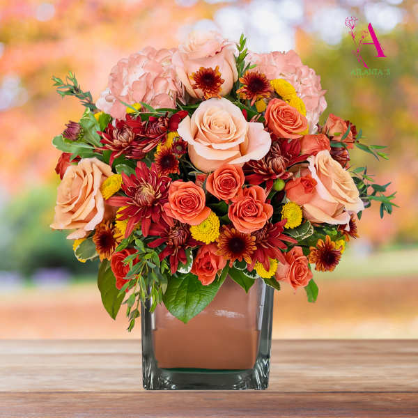 Peach and coral roses with pink hydrangeas in a square glass vase