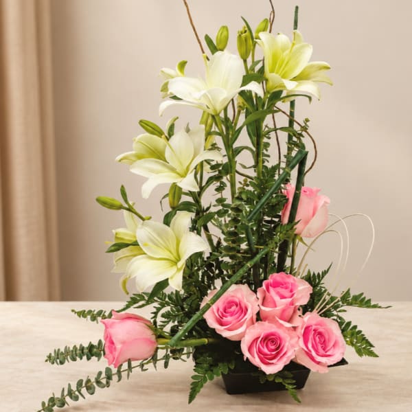 Pink roses and white lilies arranged in a black vase