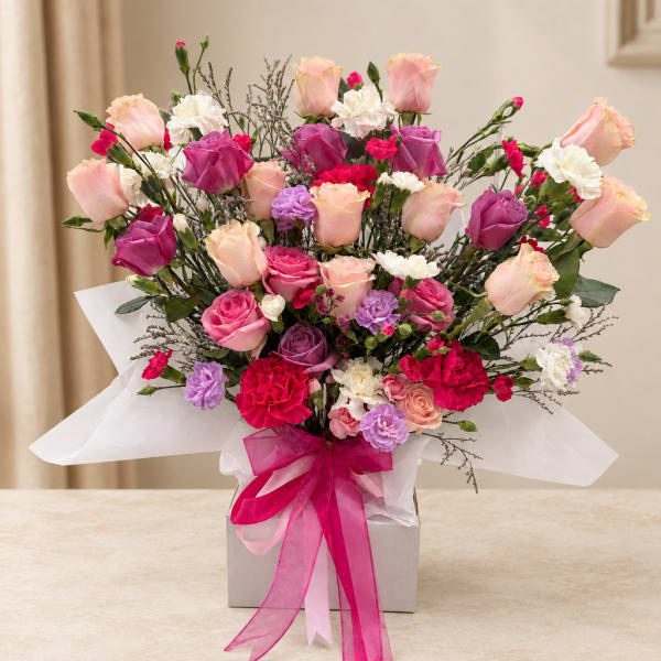 Bouquet of pink and purple roses with white carnations in a box