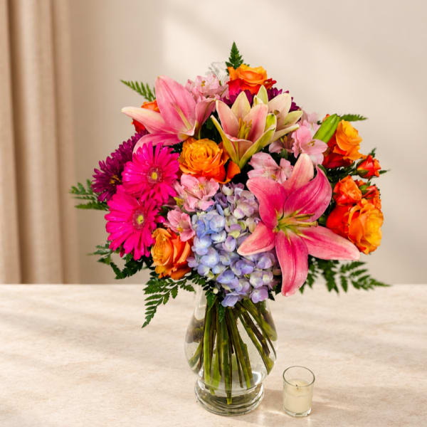 Colorful bouquet of lilies, roses, gerberas, and hydrangea in a glass vase