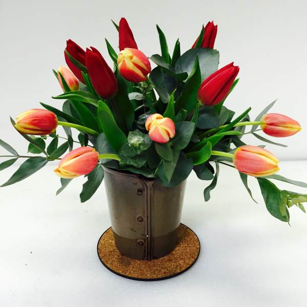 Red and peach tulips arranged in a metal pot