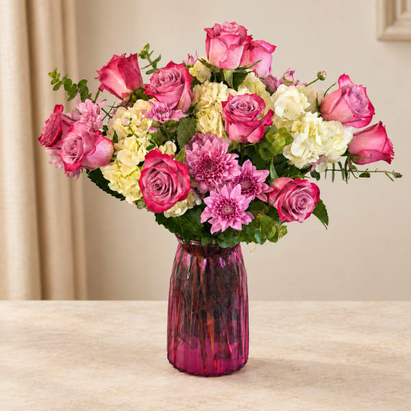 Pink roses and chrysanthemums in a magenta glass vase