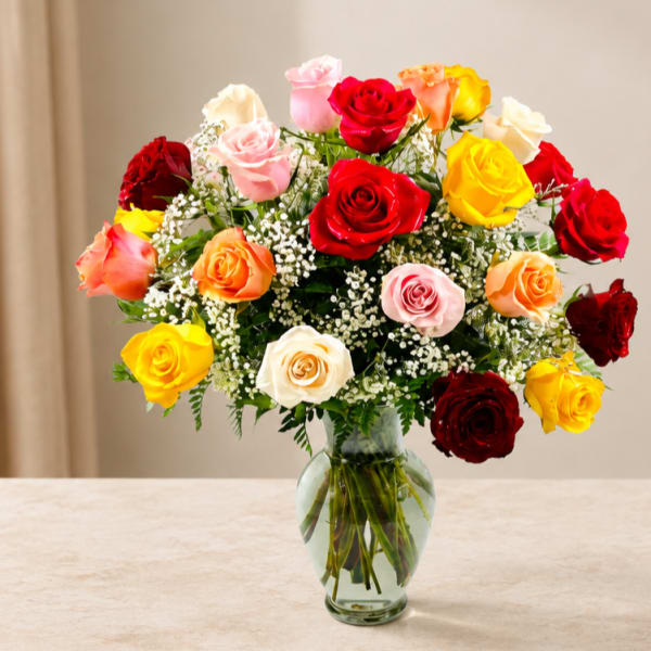 Mixed roses in red, pink, yellow, peach, and white in a clear glass vase