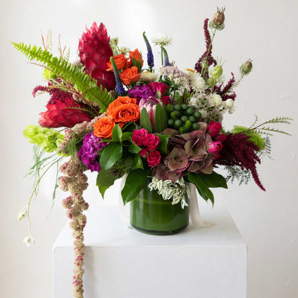 Colorful mixed flower arrangement in a green glass vase