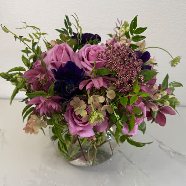 Pink roses and dark purple flowers in a clear glass vase