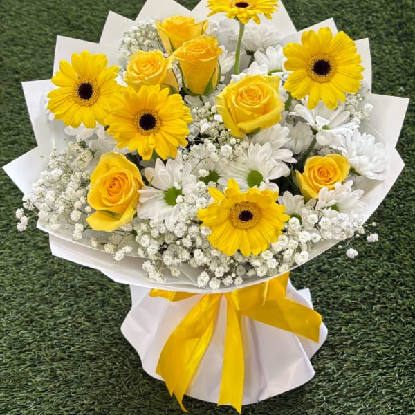 Yellow roses and gerbera daisies in white wrapping with a yellow ribbon