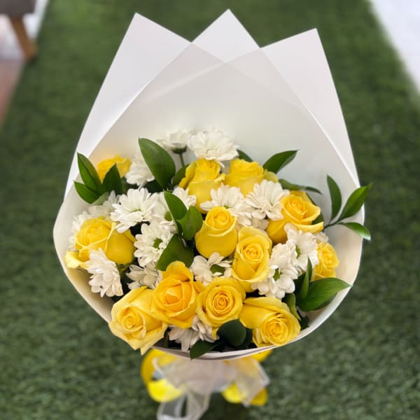 Bouquet of yellow roses and white daisies wrapped in white paper