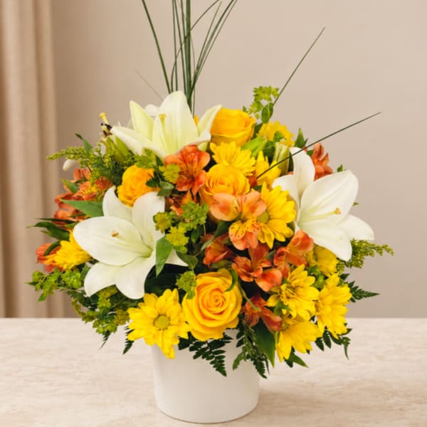 Yellow and white floral arrangement in a white vase