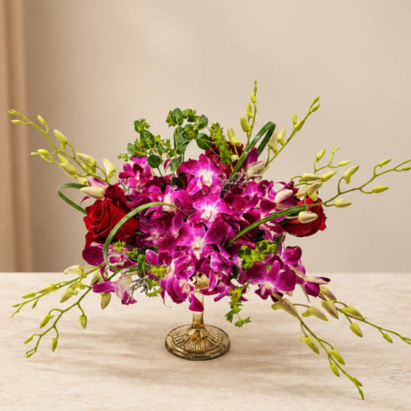 Pink orchids and red roses arranged in a gold vase