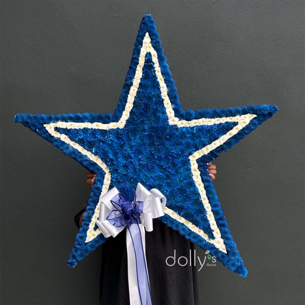Large blue and white star-shaped floral tribute with a ribbon bow