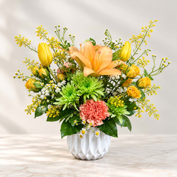 Yellow and peach floral arrangement in a white vase