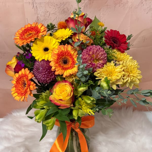 Bright mixed bouquet with gerbera daisies, roses, and dahlias in a glass vase