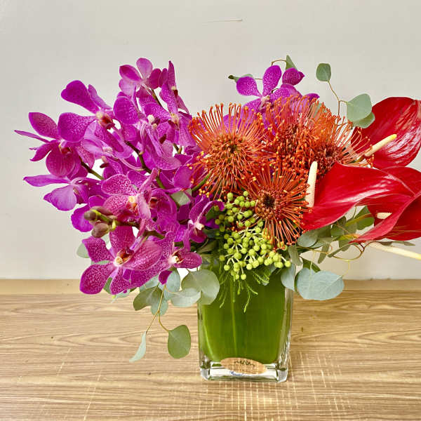 Bright orchid and anthurium arrangement in a glass vase