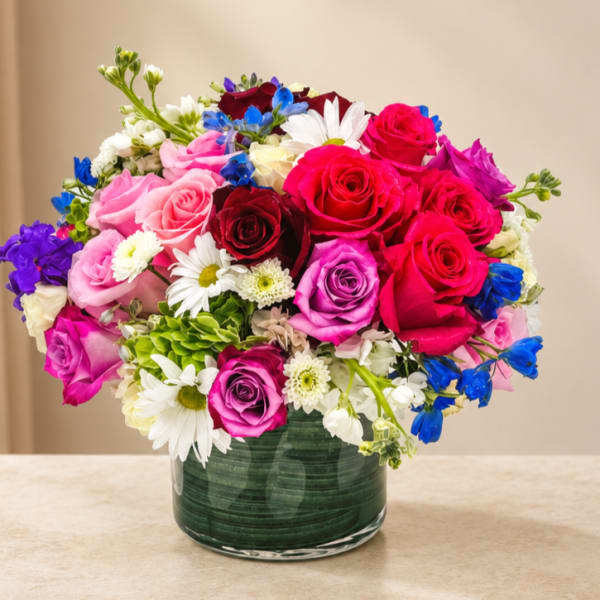 Mixed bouquet of roses and daisies in a green glass vase