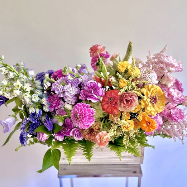 Colorful mixed flower arrangement in a wooden box on a stand