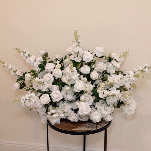 Large white floral arrangement with roses and blossoms on a round table