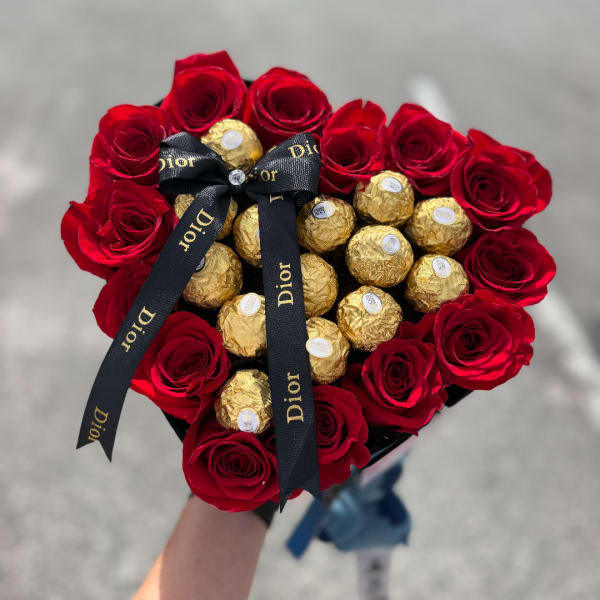 Heart-shaped bouquet of red roses with gold-wrapped chocolates and a black ribbon