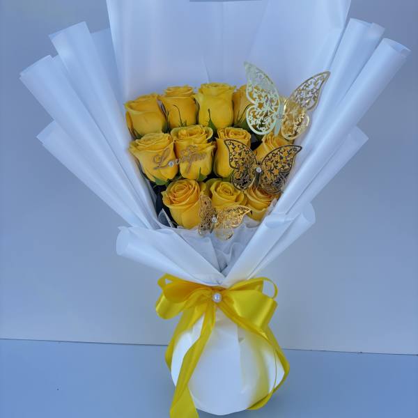 Bouquet of yellow roses wrapped in white paper with a yellow ribbon