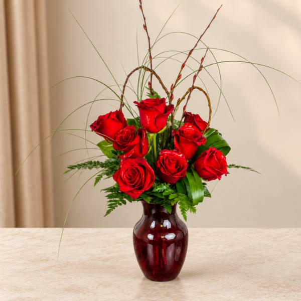 Red roses arranged in a burgundy glass vase