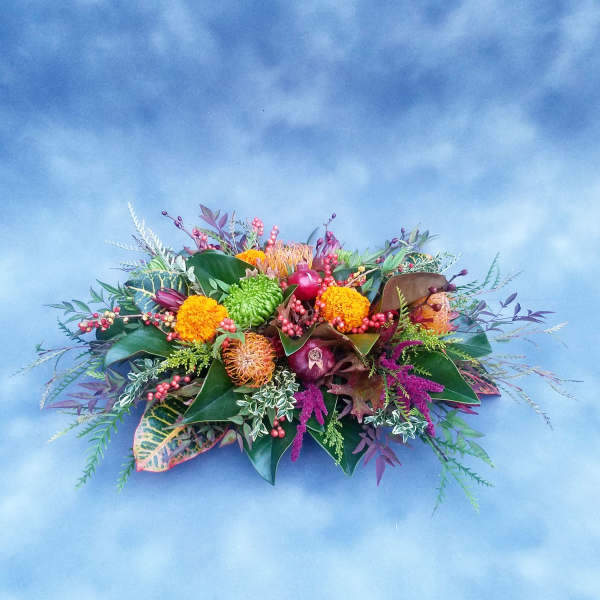 Low floral arrangement with orange, green, and purple blooms
