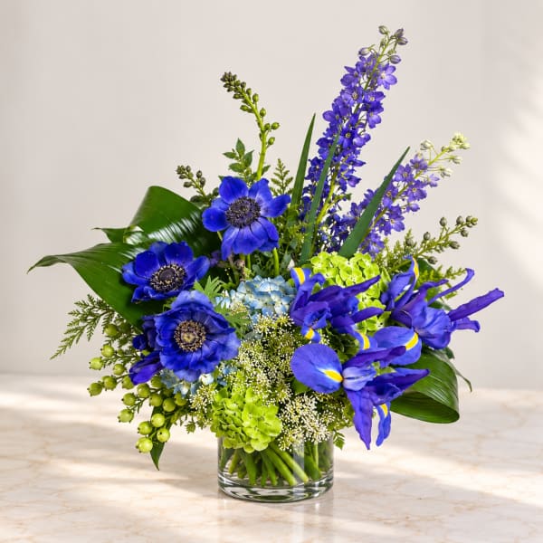 Blue and purple floral arrangement in a clear glass vase