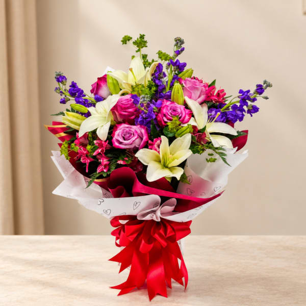 Bouquet of pink roses and white lilies wrapped with a red ribbon