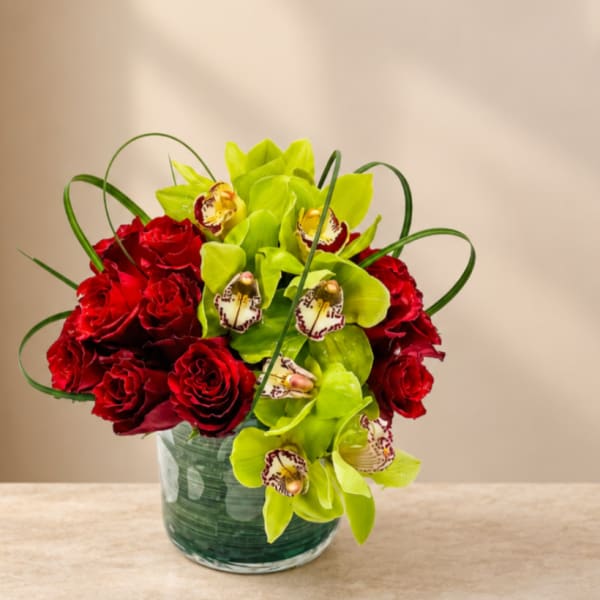 Red roses and green orchids in a glass vase