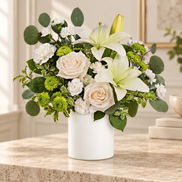 White lilies and cream roses in a white vase with green accents