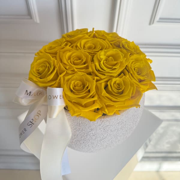 Yellow roses arranged in a white round box with a ribbon bow