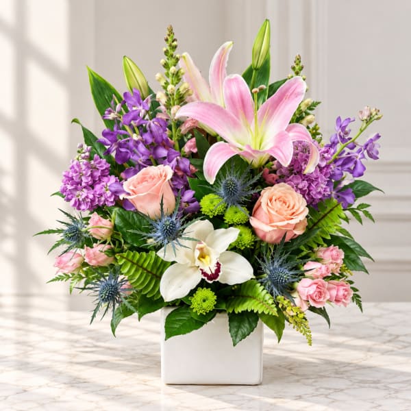 Pink lilies and roses in a white square vase with purple blooms