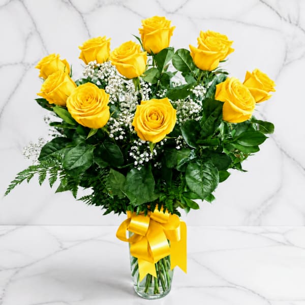 Yellow roses in a glass vase with a yellow ribbon