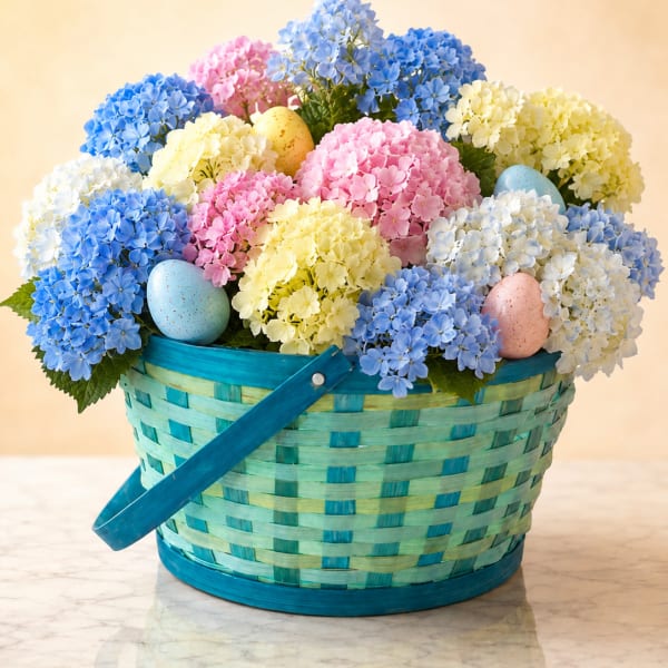 Basket of pastel hydrangeas with decorated eggs