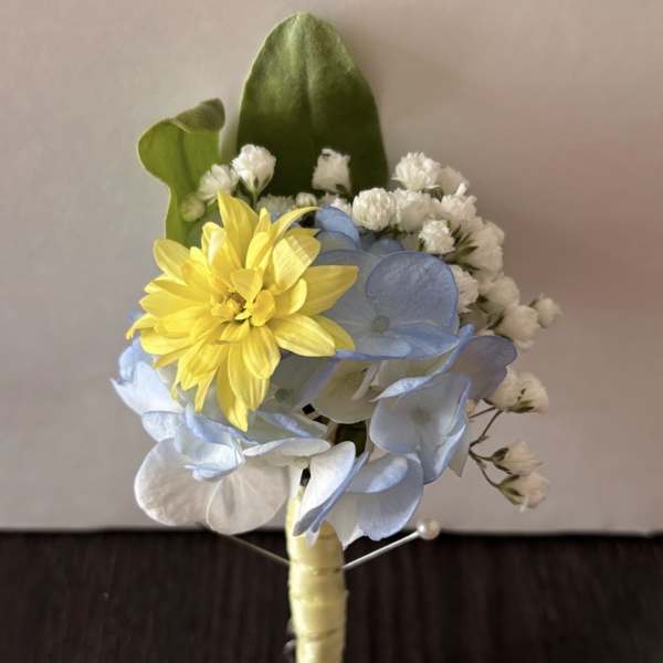 Small boutonniere with yellow and blue flowers and white accents