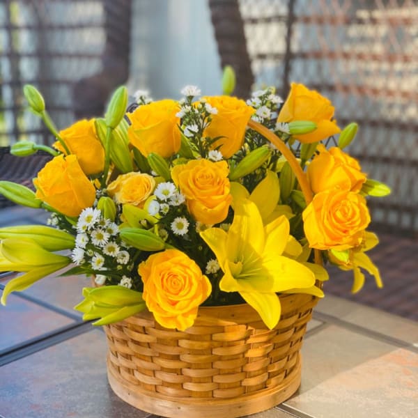 Yellow roses and lilies arranged in a woven basket