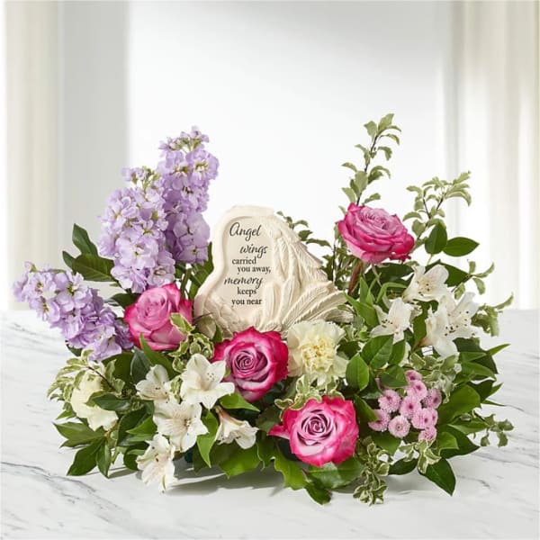 Pink and lavender floral tribute with a memorial stone centerpiece