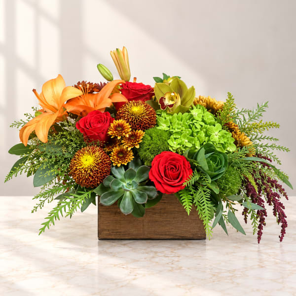 Mixed floral arrangement in a wooden box with roses, lilies, and succulents