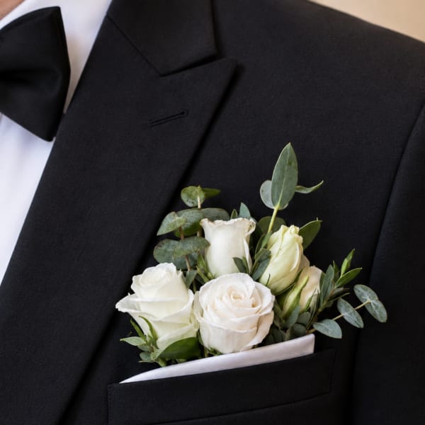 White rose boutonniere in a black suit pocket