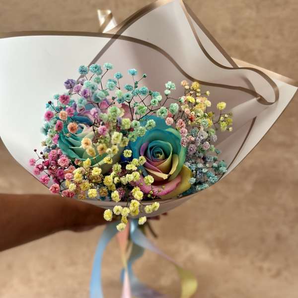 Bouquet of rainbow-colored roses with pastel baby's breath