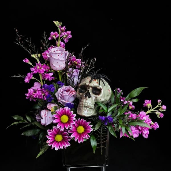 Skull centerpiece with pink and purple flowers in a black vase