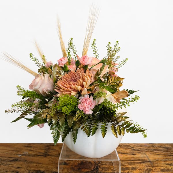 Pink and peach floral arrangement in a white bowl vase