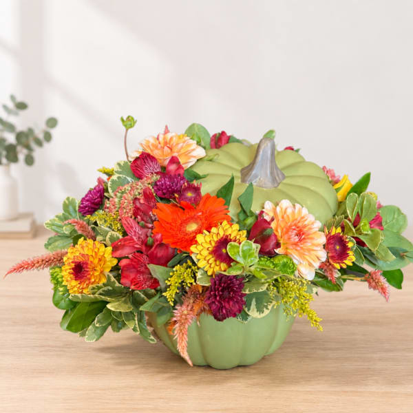Colorful flower arrangement in a green pumpkin-shaped container