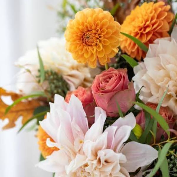 Bouquet of orange dahlias, pink roses, and pale white flowers
