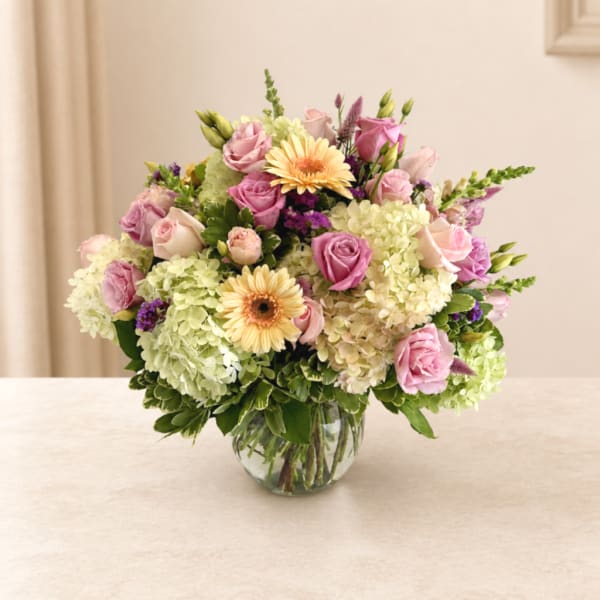 Pink roses and pale hydrangeas in a clear glass vase