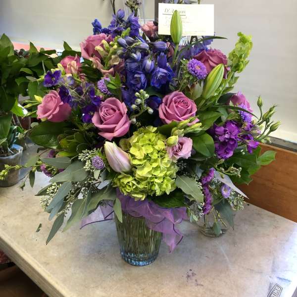 Mixed bouquet of purple, pink, and green flowers in a glass vase