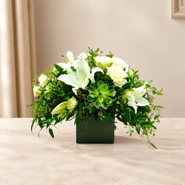 White lilies and roses in a dark square vase
