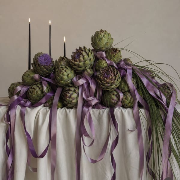 Artichoke centerpiece with purple ribbons and tall black candles
