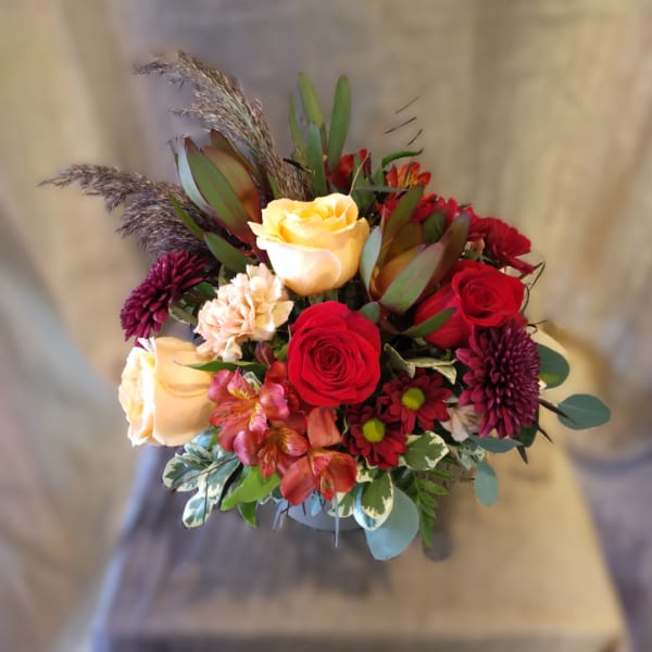 Bouquet of red and cream roses with purple mums in a vase