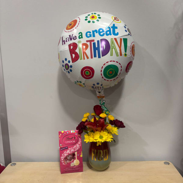 Birthday balloon above a flower vase and a box of chocolates