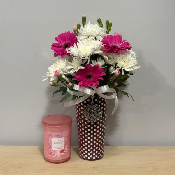Pink and white daisy bouquet in a polka-dot vase with a ribbon