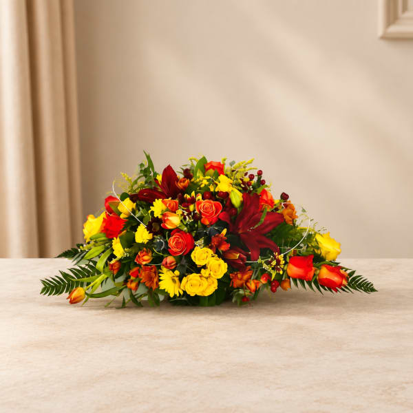 Low bouquet of red, yellow, and orange flowers on a table